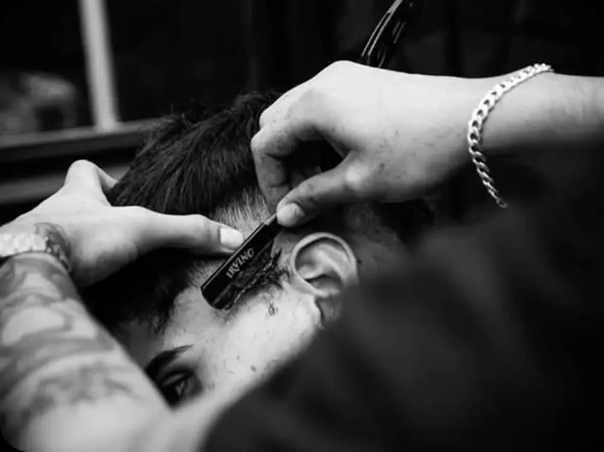 Barbier traçant un contour à la lame derrière l'oreille